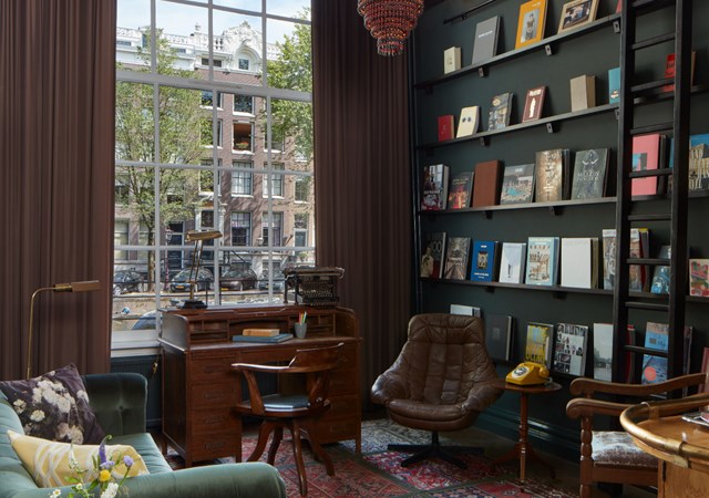 A spacious living room featuring a large window and filled bookshelves, creating a cozy and inviting atmosphere.