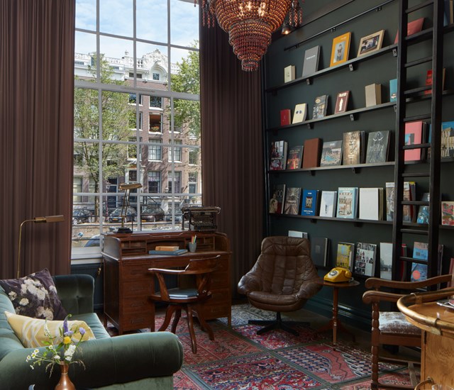 A spacious living room featuring a large window and filled bookshelves, creating a cozy and inviting atmosphere.