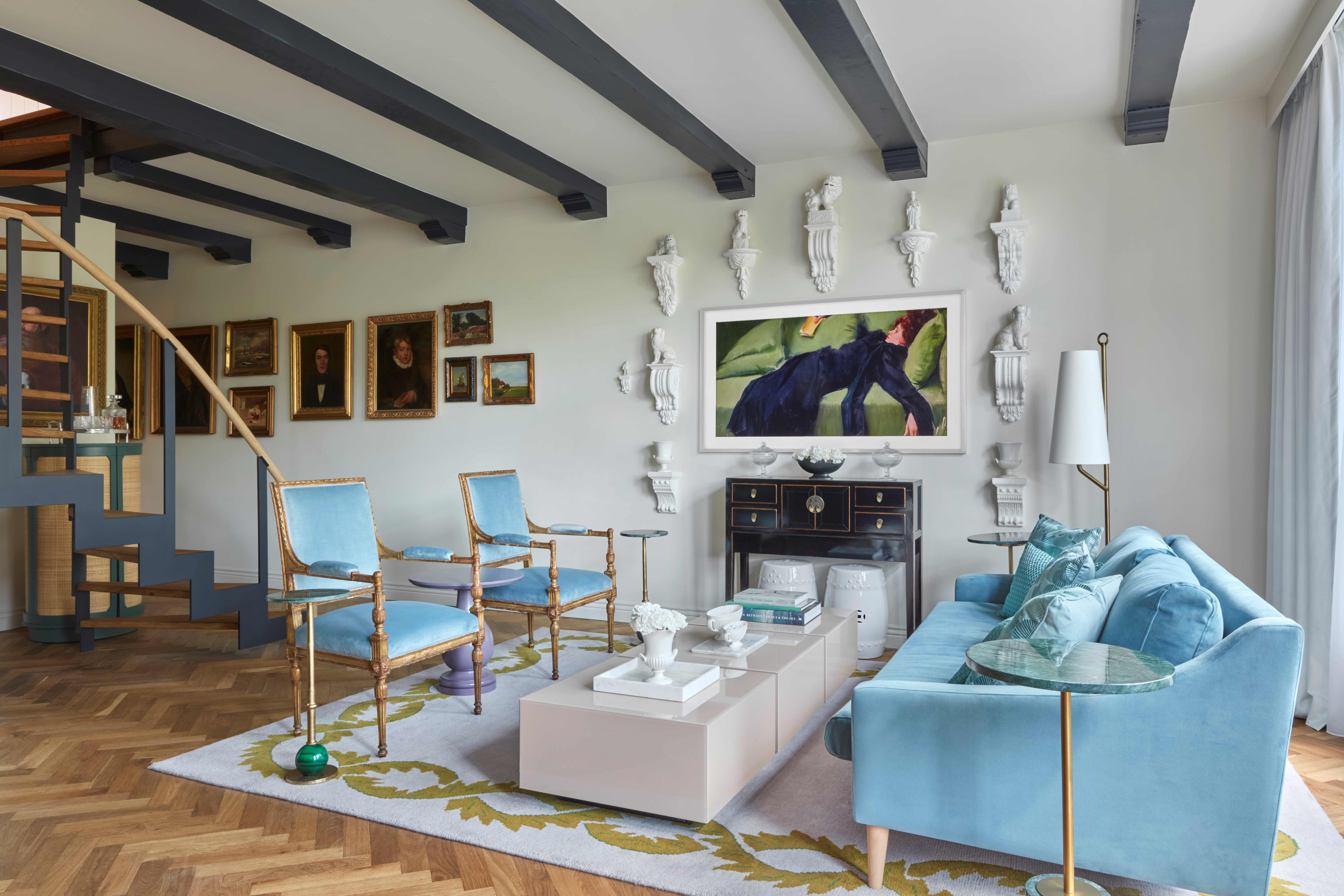 A stylish living room showcasing blue furniture complemented by a colorful painting on the wall, enhancing the decor.