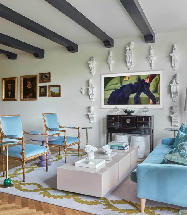 A stylish living room showcasing blue furniture complemented by a colorful painting on the wall, enhancing the decor.