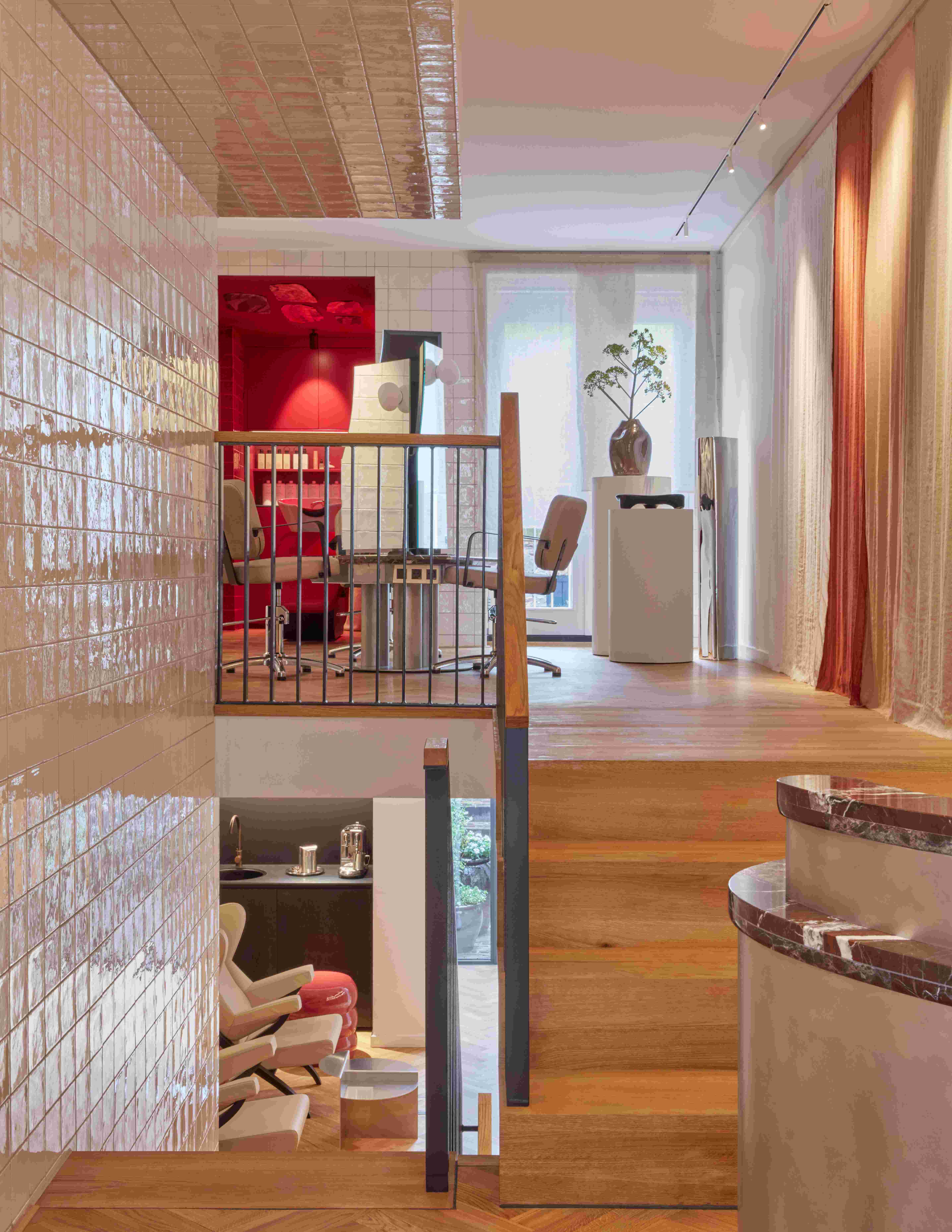 A stairway ascending to a room featuring a vibrant red wall, creating a striking visual contrast at a beauty salon in Amsterdam.