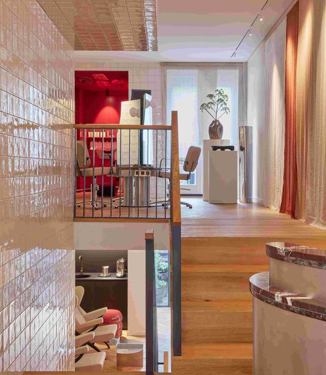 A stairway ascending to a room featuring a vibrant red wall, creating a striking visual contrast at a beauty salon in Amsterdam.