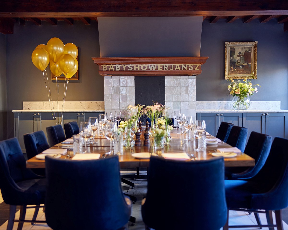 Dining room setup for a baby shower with gold balloons, navy chairs, and a sign over the fireplace reading Baby Shower Jansz.