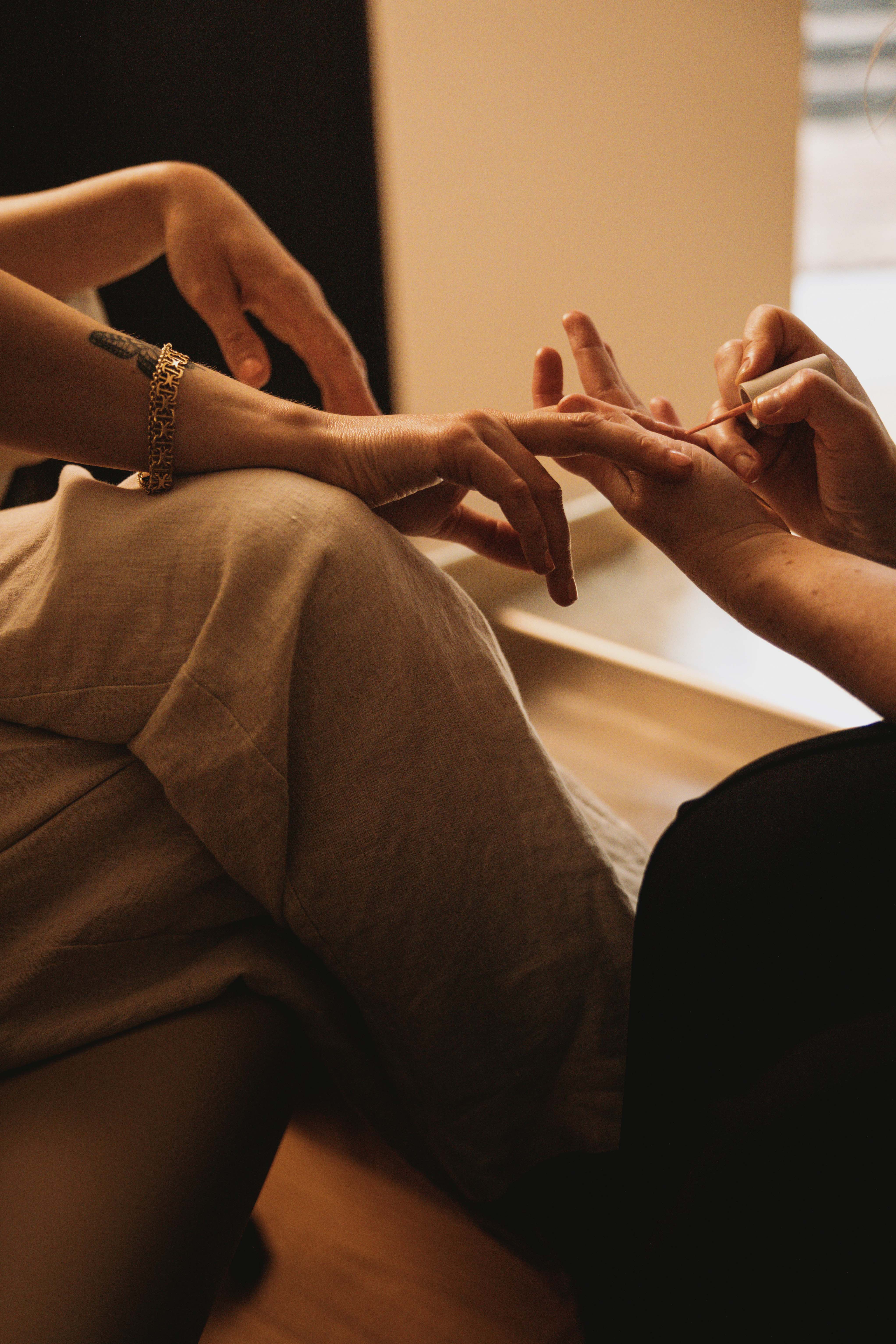 Close-up of a hand receiving a manicure, with a relaxed pose and gentle lighting.