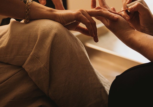 Close-up of a hand receiving a manicure, with a relaxed pose and gentle lighting.