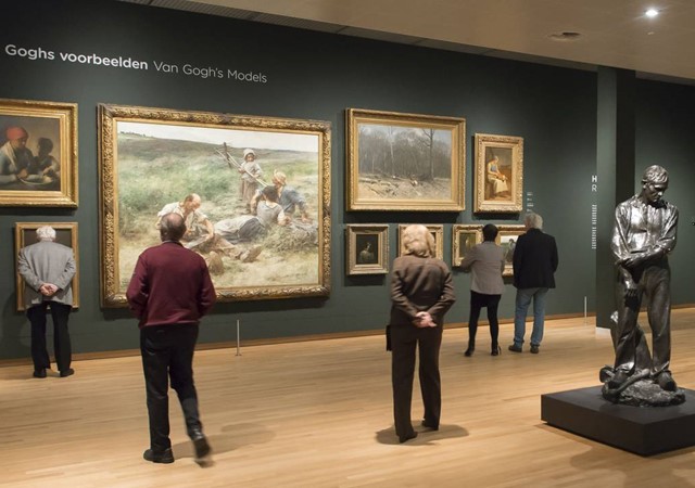 Visitors admire various paintings and sculptures displayed in the Van Gogh museum, engaging with the artwork around them.