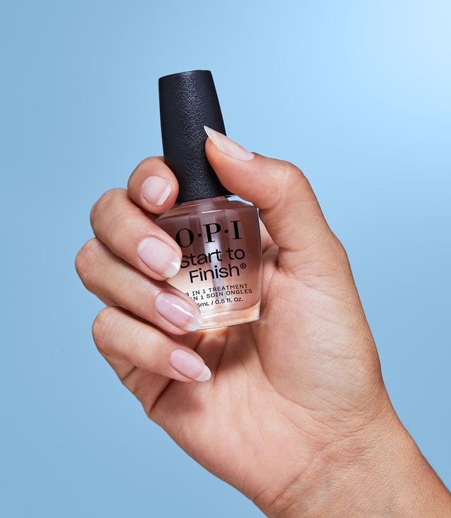 Close-up of a woman's hand grasping a bottle of OPI nail polish, highlighting its stylish packaging and rich hue.