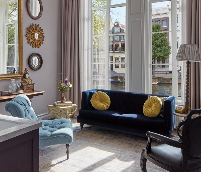 A bright living room with a large window allowing natural light, showcasing a modern bathtub as a focal point.