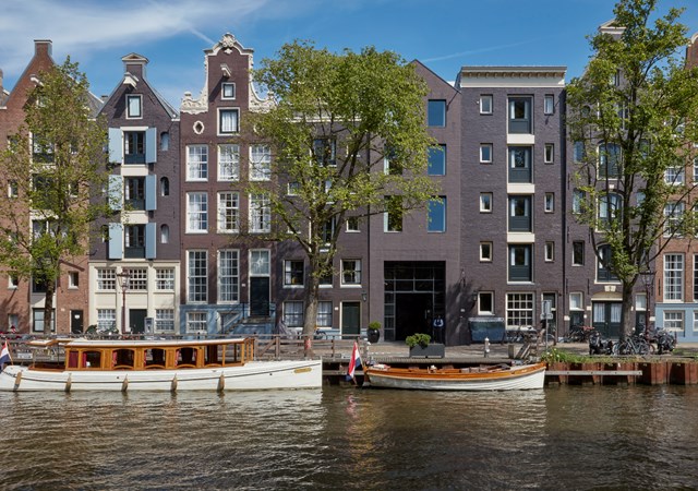 A boat is securely docked in front of a row of charming buildings along the waterfront in Amsterdam.