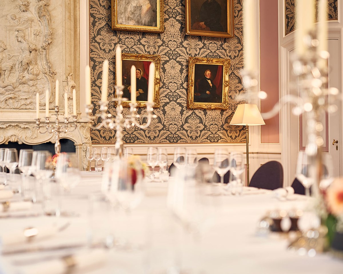 A long table elegantly set with white linen and flickering candles, creating a warm and inviting atmosphere.