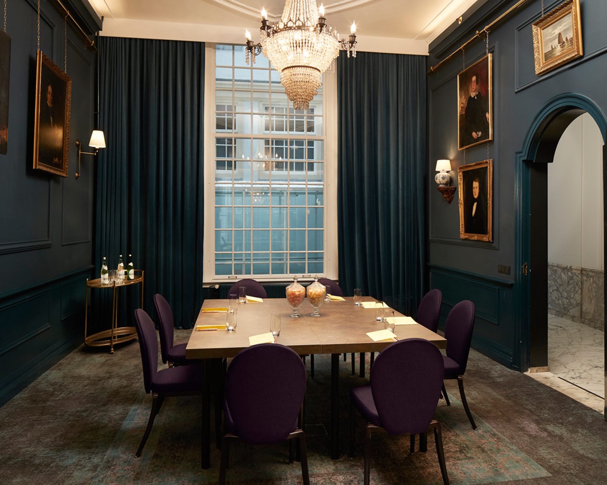 A dining room featuring elegant purple chairs and a stunning chandelier overhead, creating a sophisticated atmosphere.