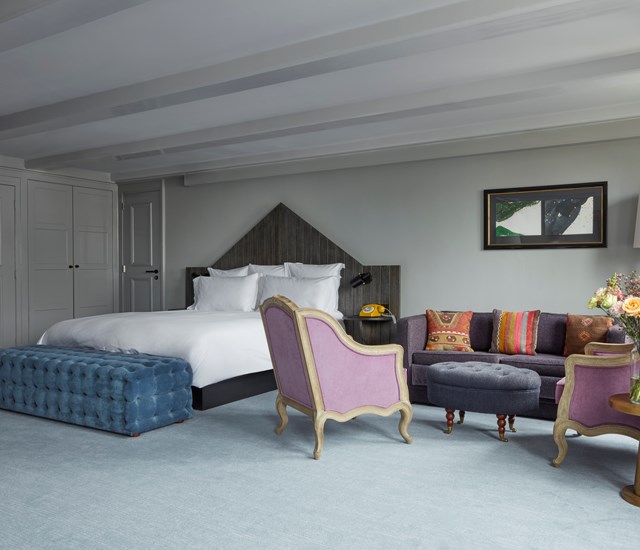 A well-furnished hotel room showcasing a bed, a chair, and a couch for guests' comfort.