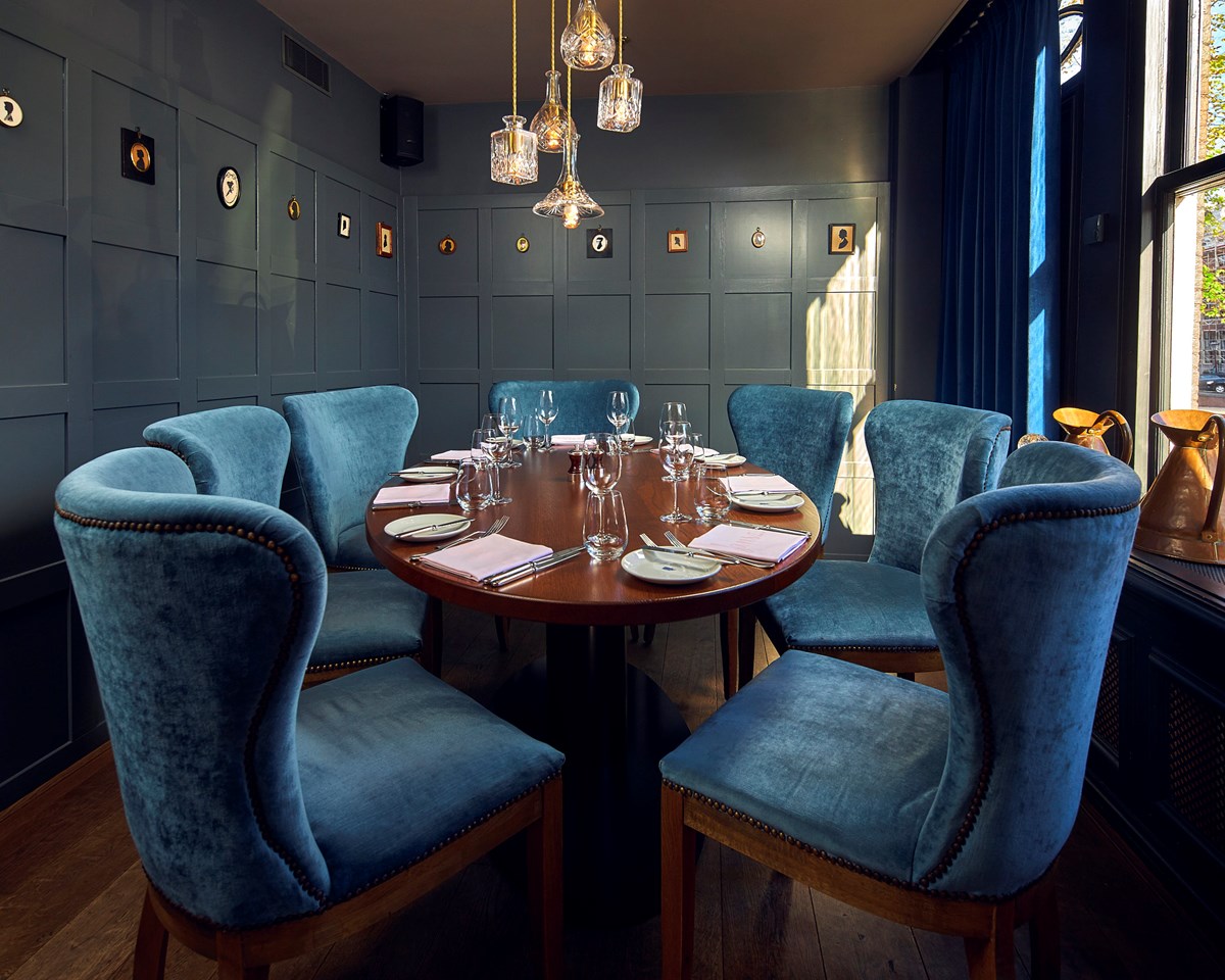 A dining room featuring elegant blue velvet chairs surrounding a stylish table, creating a sophisticated atmosphere.