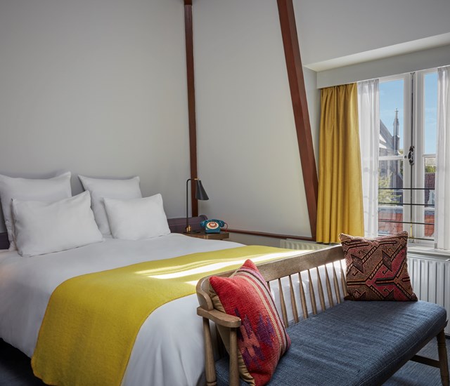 A cozy bed adorned with yellow and white blankets and pillows, creating a warm and inviting atmosphere.