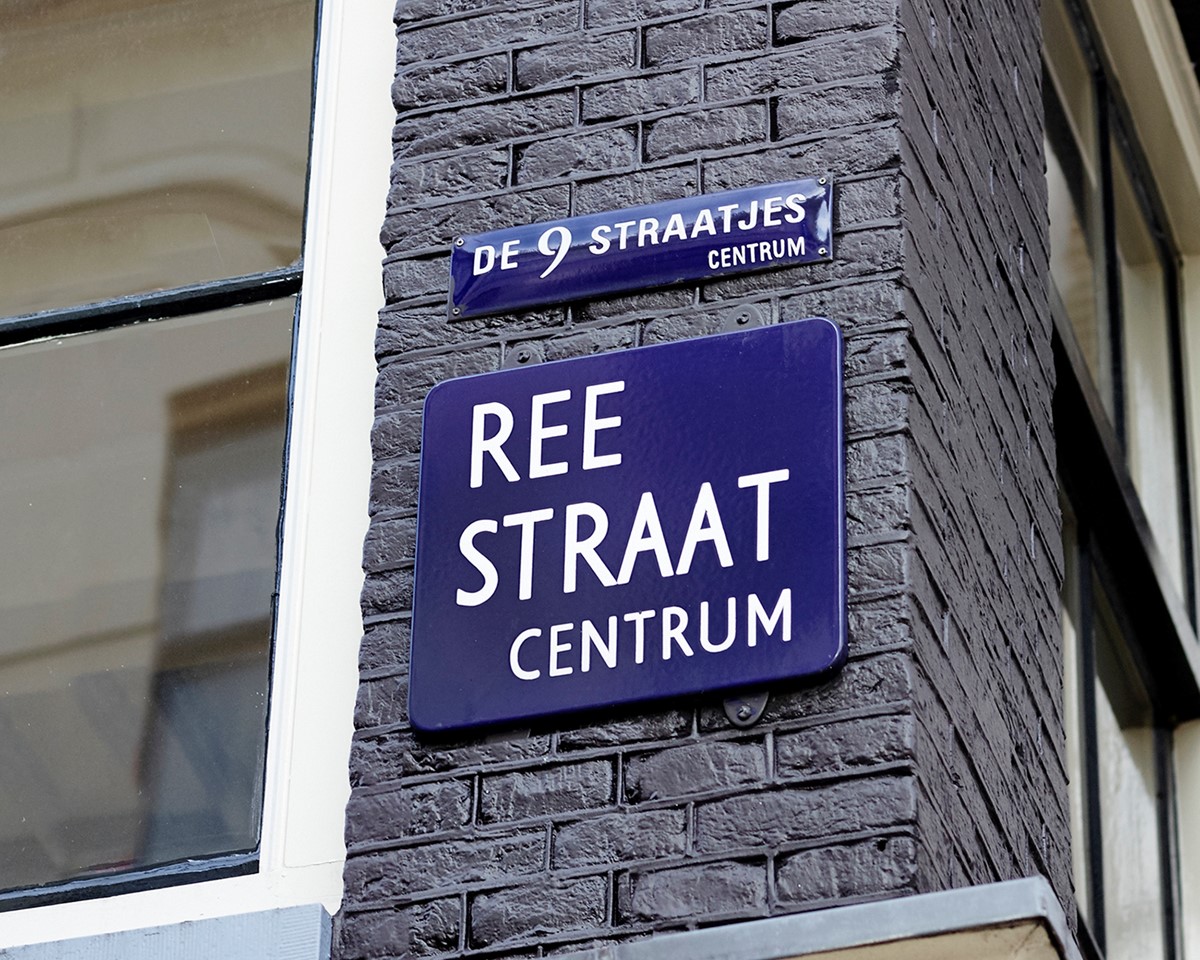 A blue and white sign mounted on a brick structure, highlighting its distinct design against the textured background.