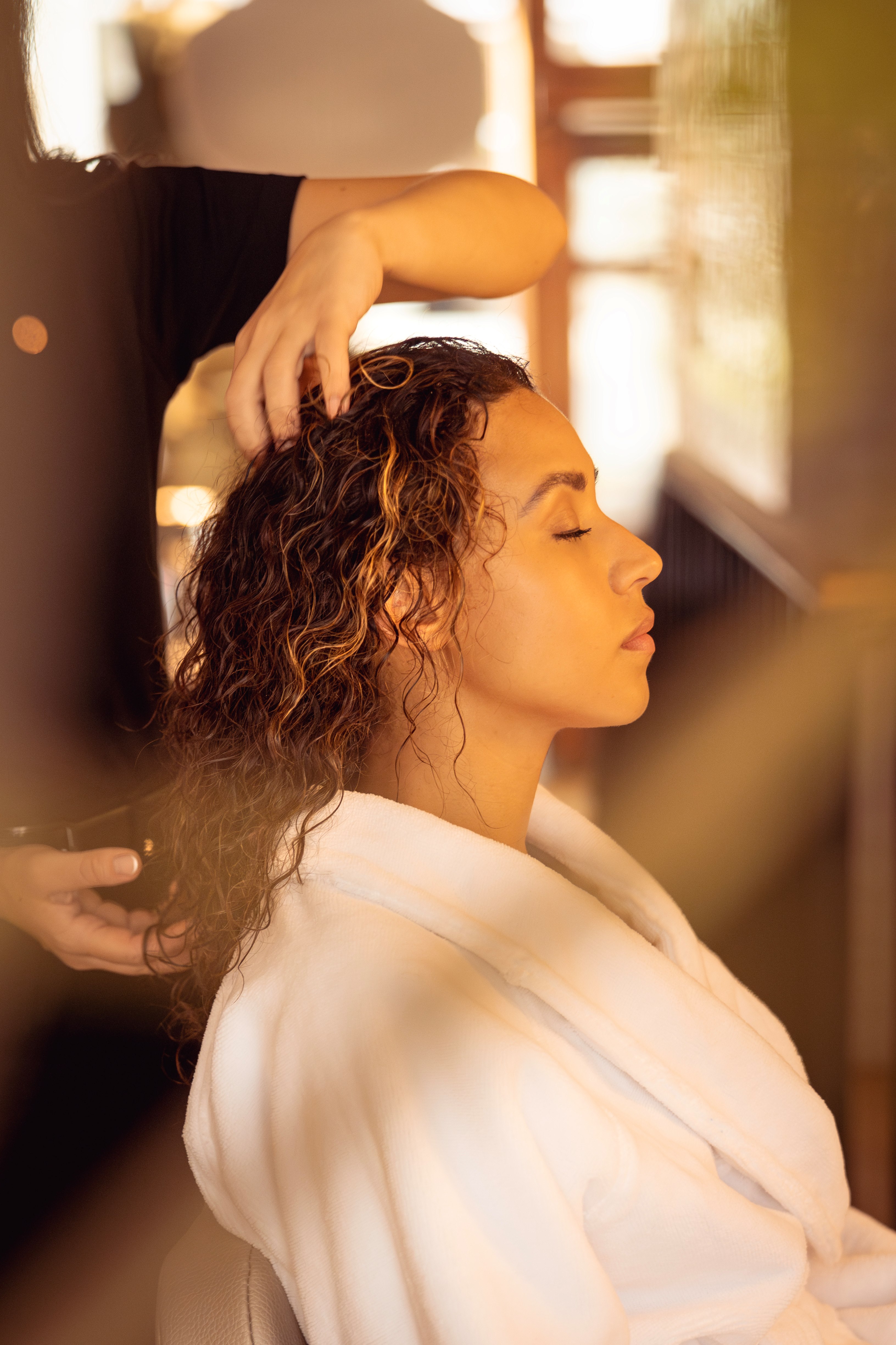 A woman is sitting in a beauty salon in Amsterdam in a white robe with the hairdresser working with her hair.