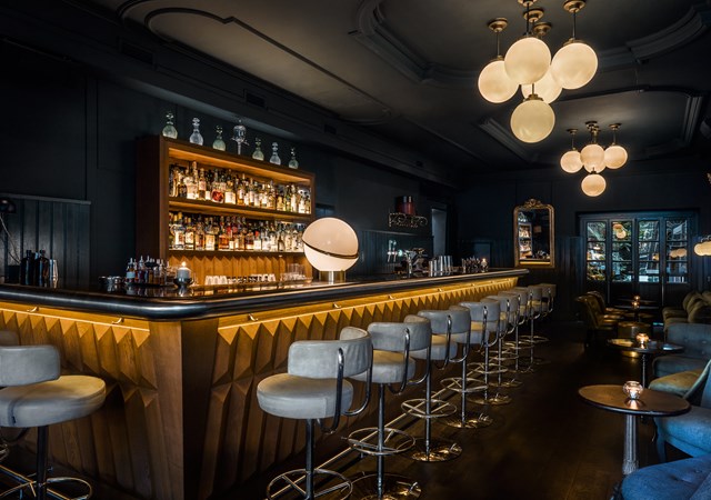 Pulitzer's bar in hotel Pulitzer Amsterdam with bar chairs and bottle display