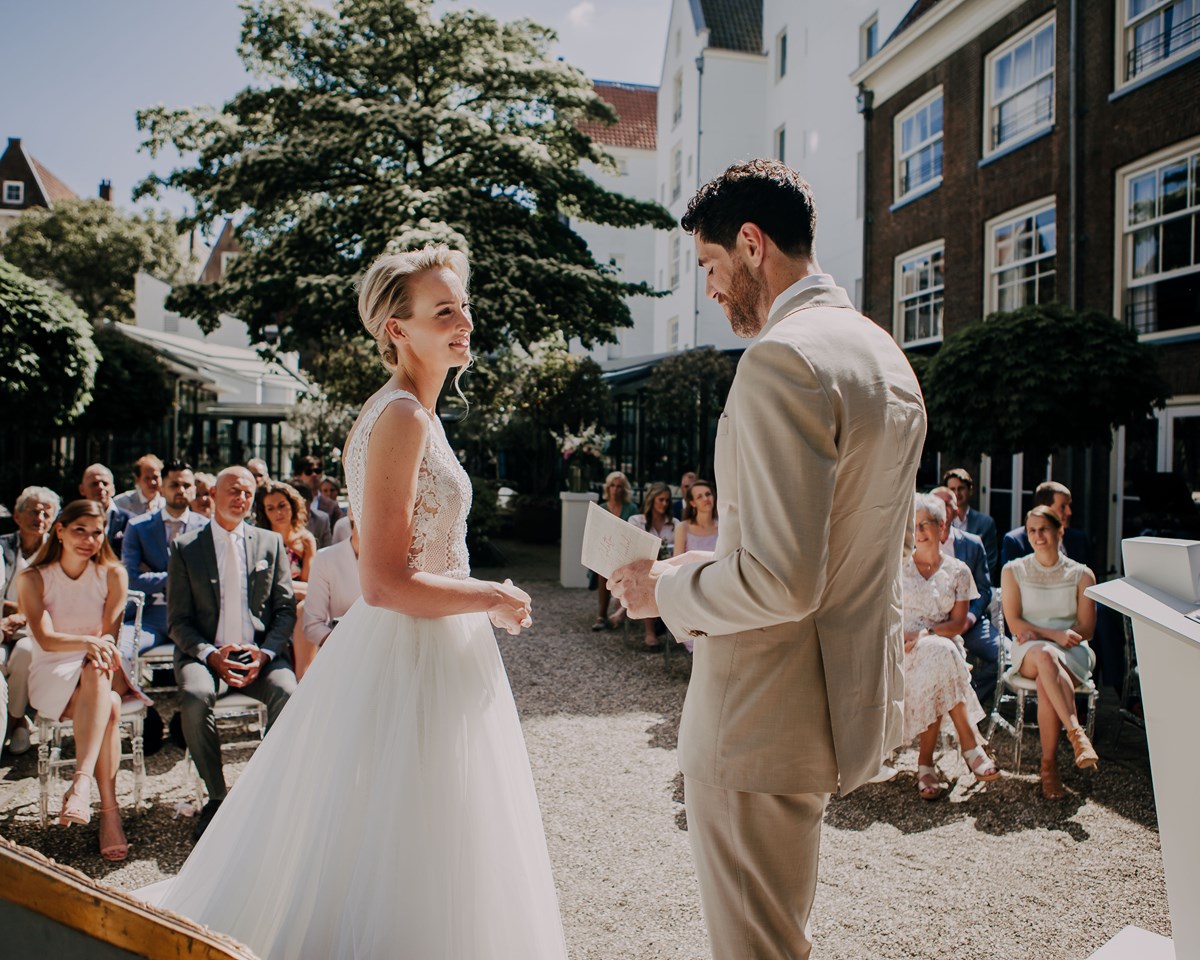 A bride and groom stand together, smiling joyfully in front of their gathered guests during a wedding ceremony.