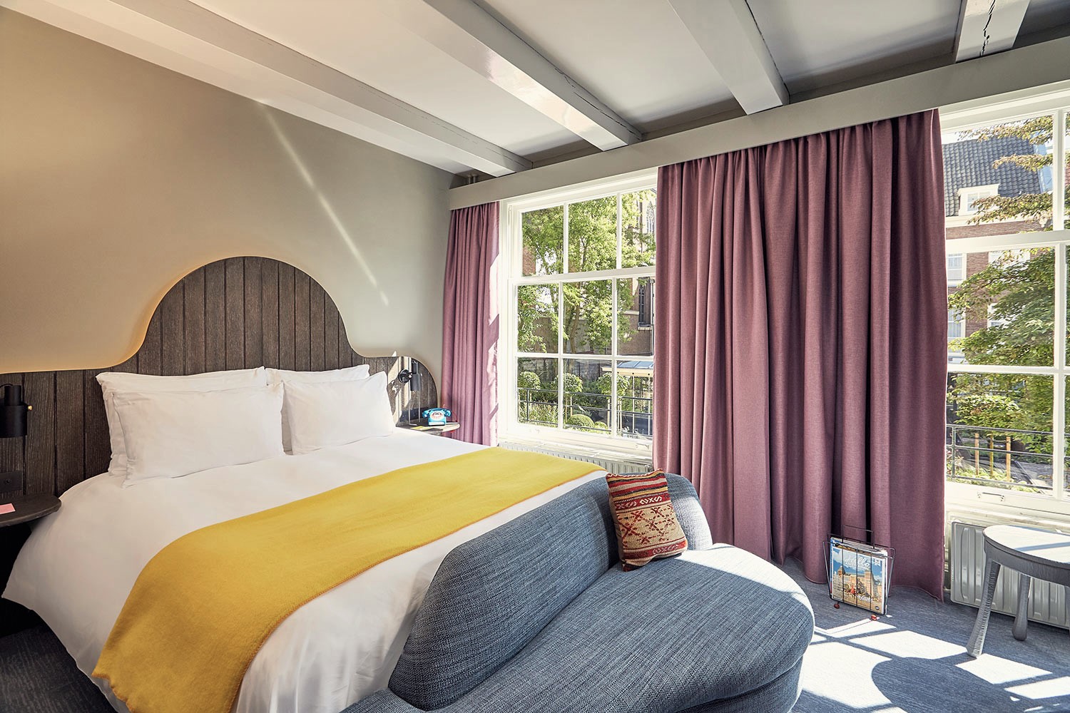 A well-furnished hotel room with a bed, an inviting chair, and a window providing a view of the outside.