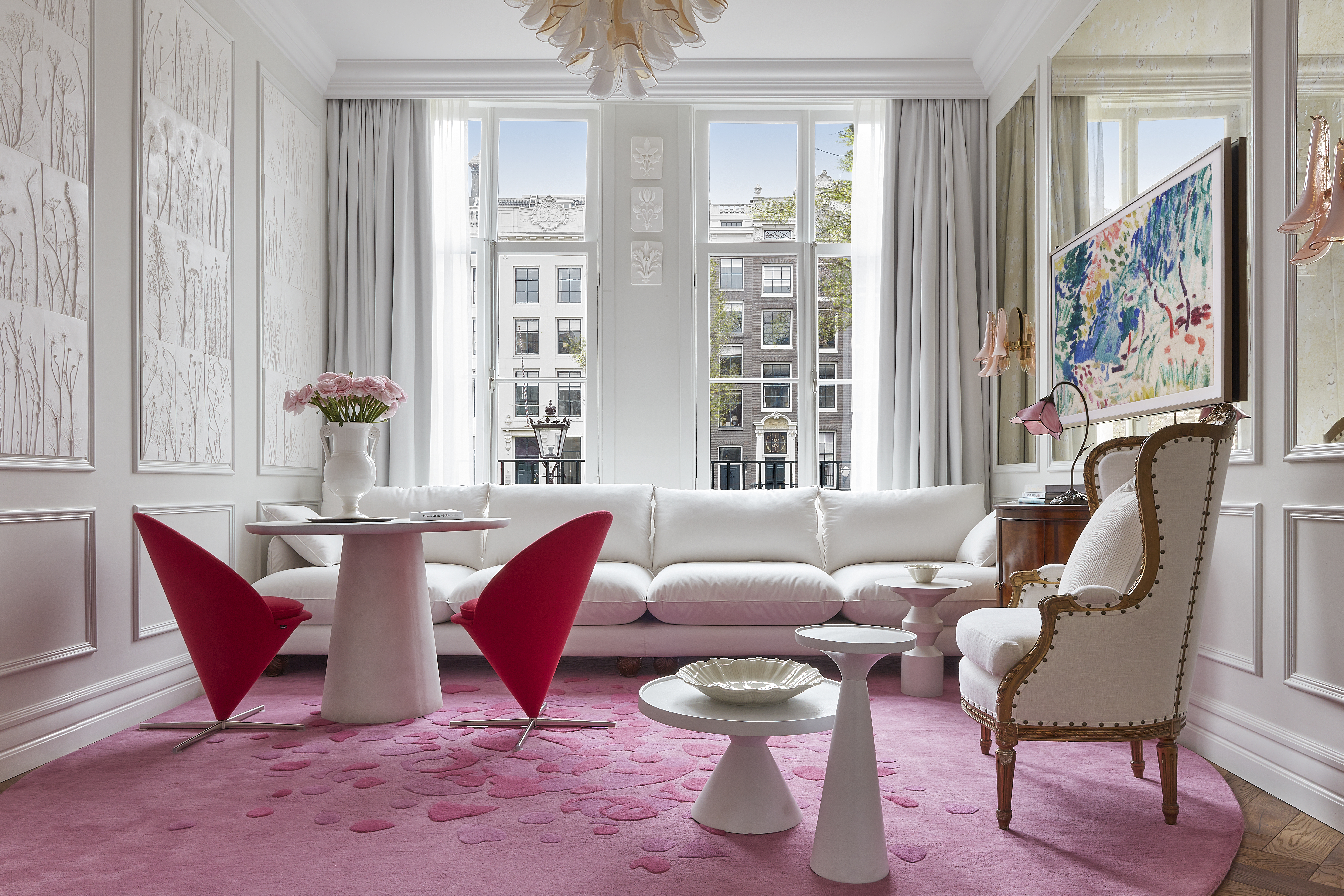 A stylish living room showcasing a pink rug and white furniture, offering a bright and cheerful ambiance for relaxation.