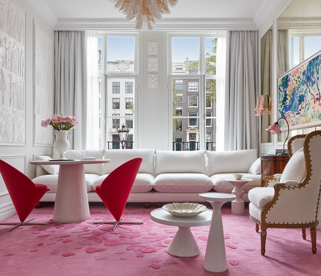 A stylish living room showcasing a pink rug and white furniture, offering a bright and cheerful ambiance for relaxation.