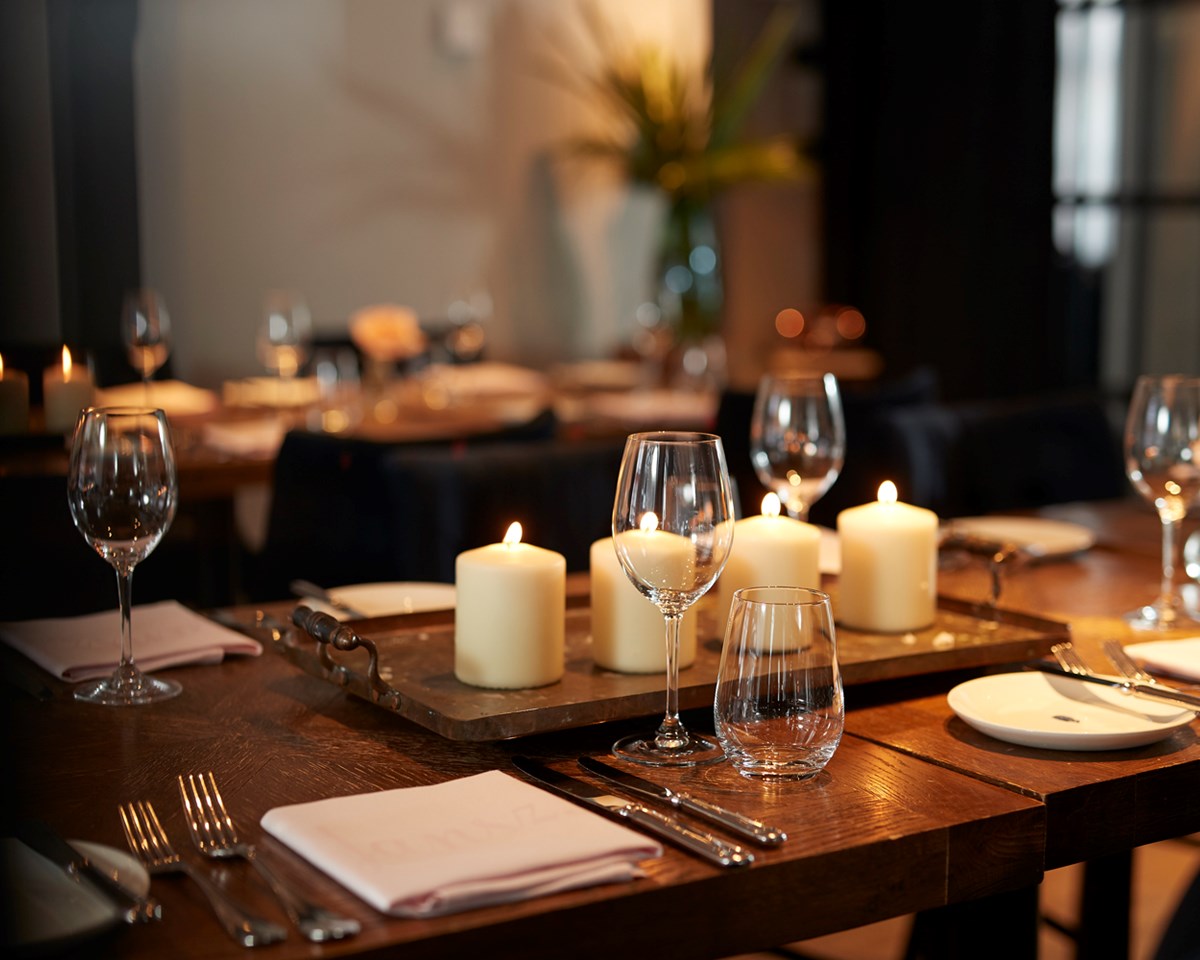 An inviting table adorned with flickering candles and carefully arranged place settings, creating a warm atmosphere.
