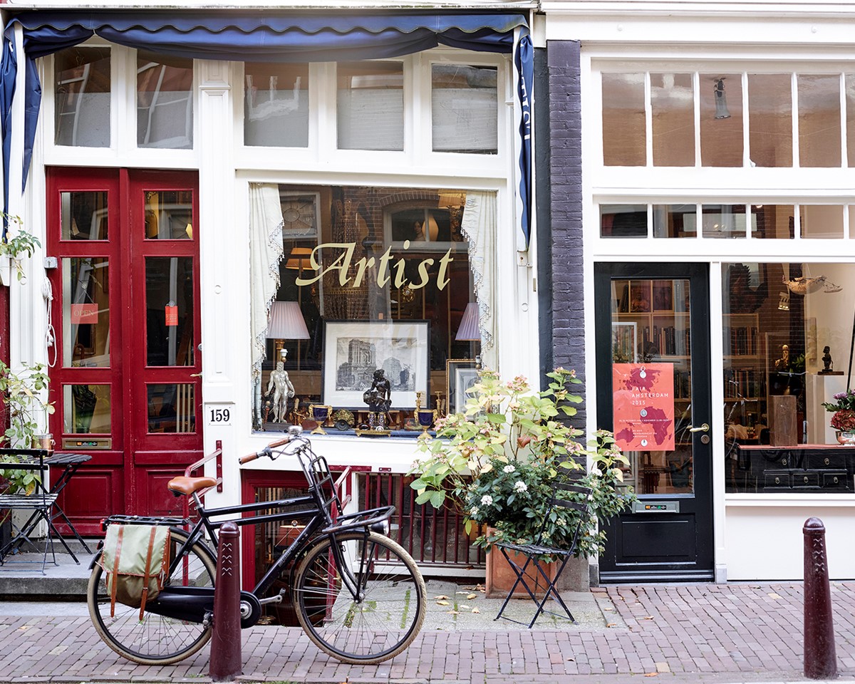 A bicycle is parked in front of a store, showcasing a vibrant urban scene with retail activity in the background.