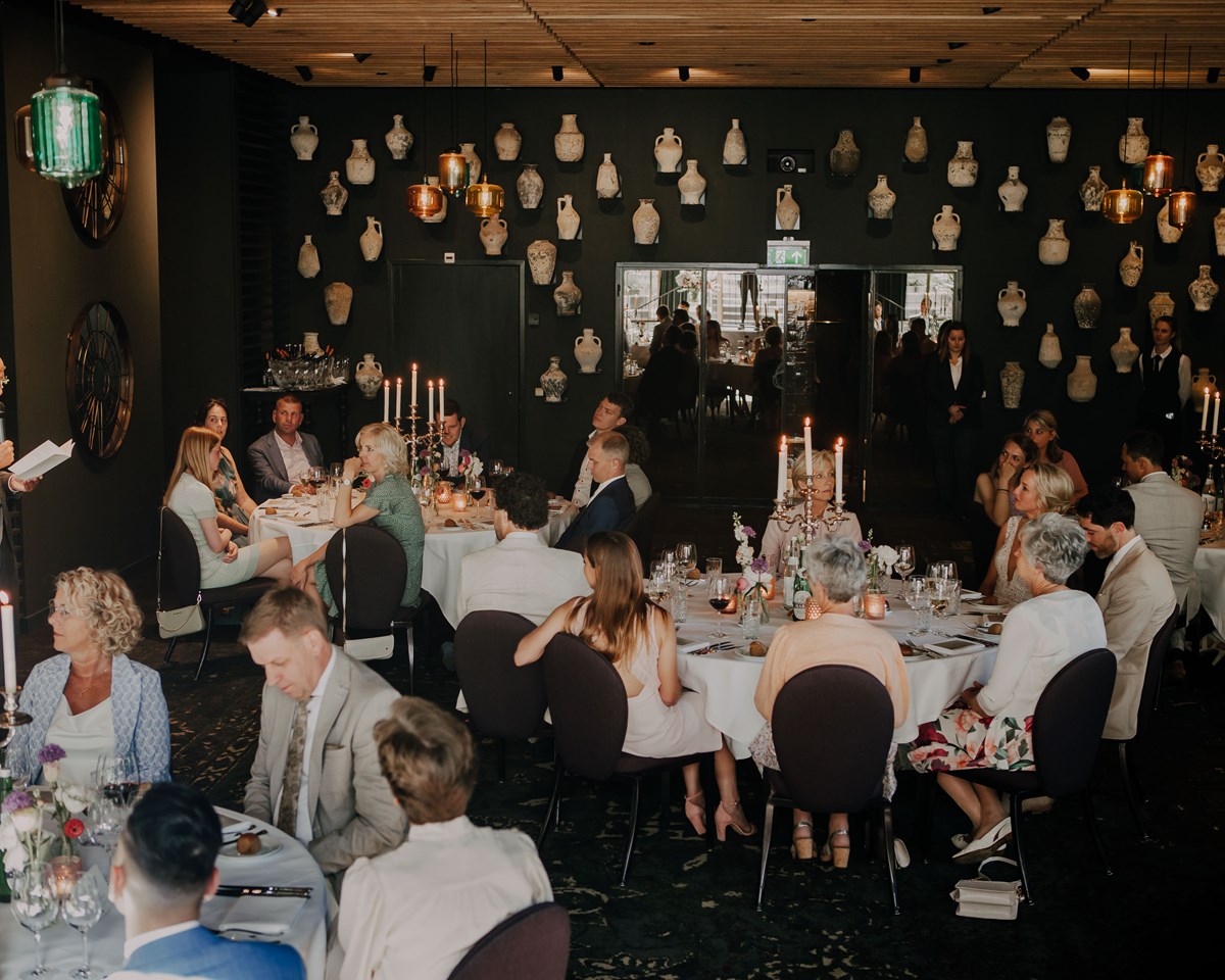A festive wedding reception scene in a restaurant, showcasing people gathered at tables, celebrating love and togetherness.