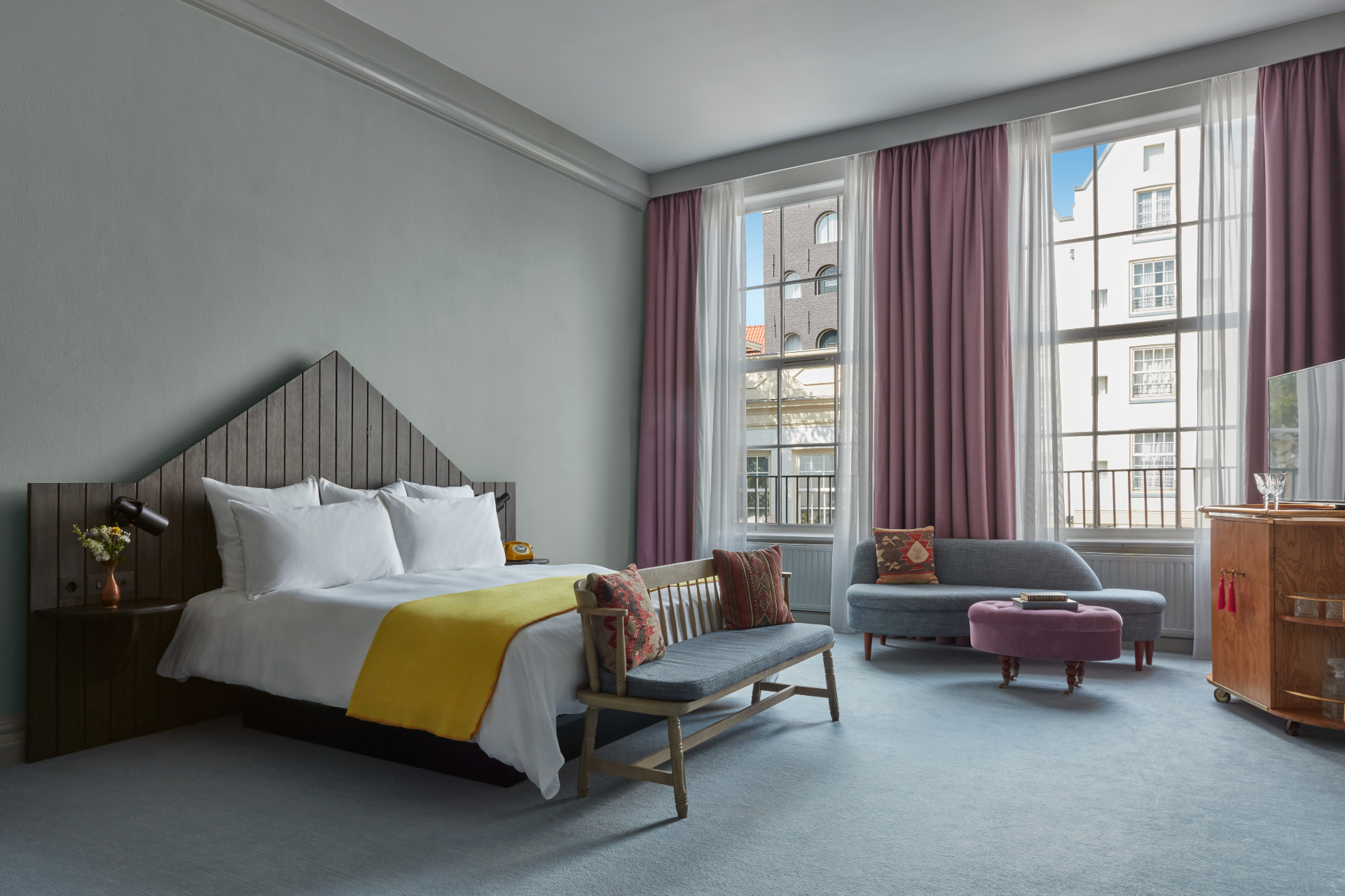 An inviting hotel room with a neatly made bed, a stylish chair, and a window providing ample daylight.