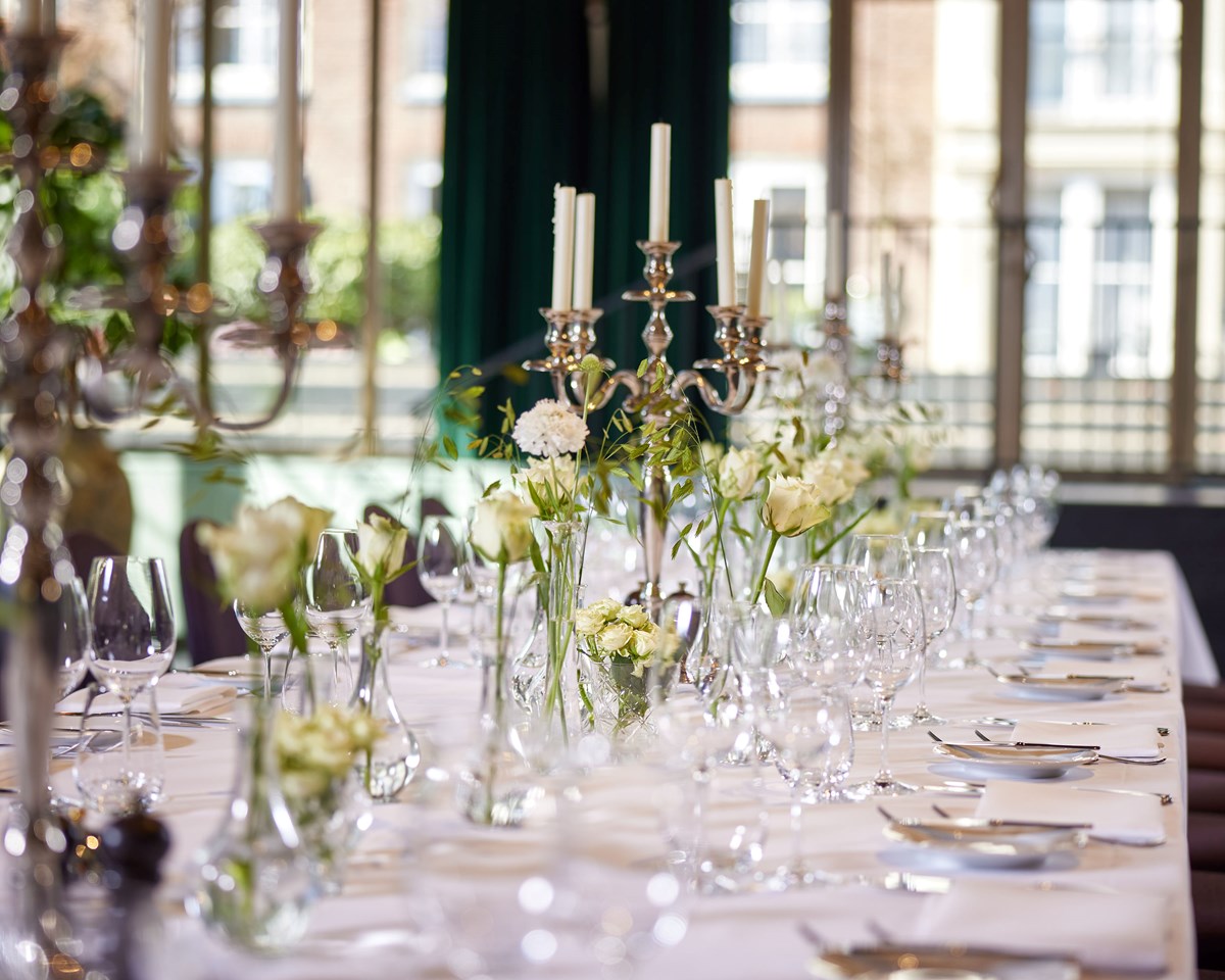A beautifully arranged long table featuring numerous white and green flowers, enhancing the setting with natural beauty.