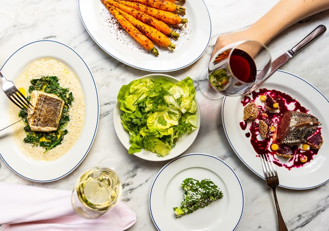 A beautifully arranged table featuring plates of food and glasses of wine, inviting a delightful dining experience.