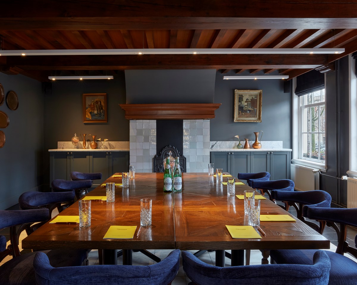 Elegant dining room with a wooden table, blue velvet chairs, and an antique fireplace.