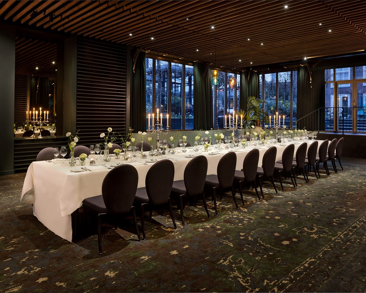 Elegant long table setup in the Garden Room at Pulitzer Amsterdam, ideal for gatherings, with stylish decor.